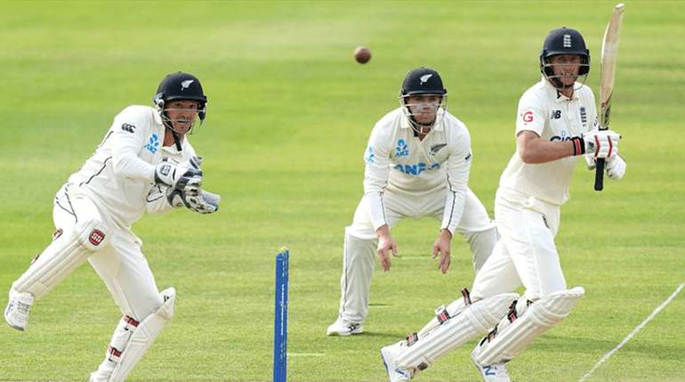 A cricket batter playing a shot with wicketkeeper and slips behind on a bright afternoon.